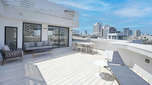 A rooftop terrace with a modern outdoor seating area, including a sofa and a table, overlooking a cityscape. - Spacious 4BR near the beach w Jacuzzi by HolyGuest (Tel Aviv-Yafo)
