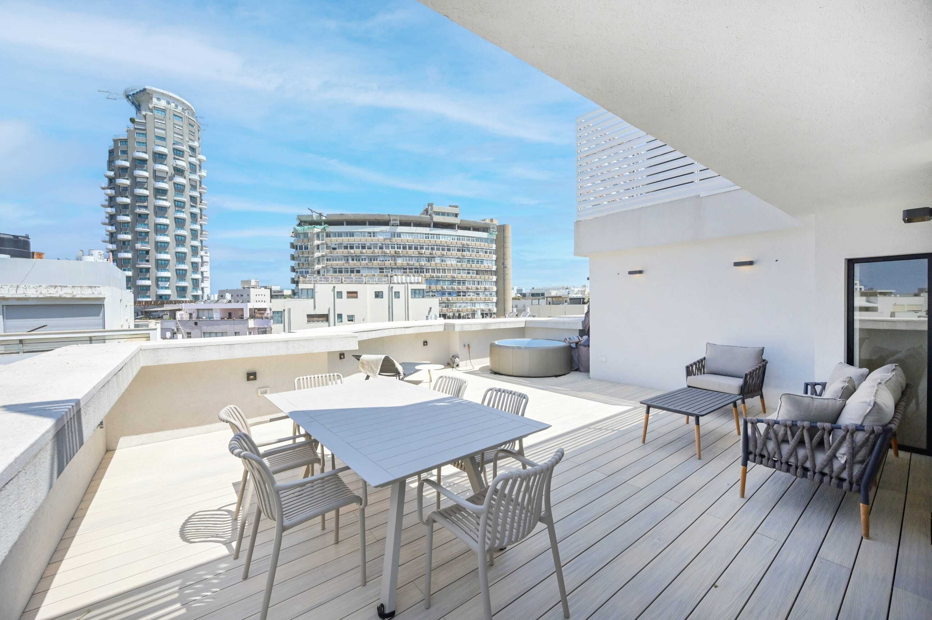 Una terrazza sul tetto con un tavolo e sedie, un divano e vista sugli edifici circostanti.