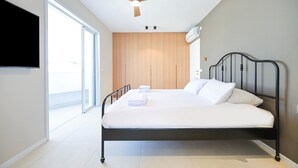 A bedroom with a bed, a ceiling fan, a TV, and a large window. - Spacious 4BR near the beach w Jacuzzi by HolyGuest (Tel Aviv-Yafo)