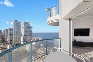 Un balcon moderne avec une balustrade en verre, offrant une vue sur le paysage urbain et l’océan.