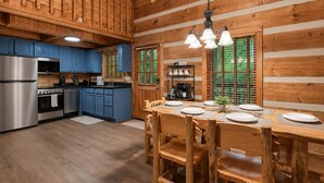 Interior de una cabaña de madera con cocina, comedor y zona de café.