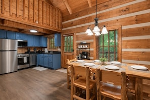 Ein Holzblockhaus-Interieur mit Küche, Essbereich und einer Kaffeestation.