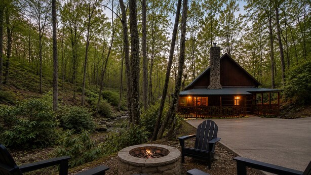 Una cabaña con chimenea de piedra, un brasero y dos sillas Adirondack.