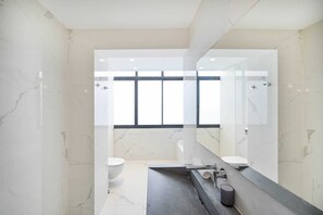 Moderni kylpyhuone, jossa on suuri peili, kylpyamme ja wc.