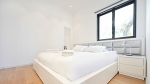 Ein modernes Schlafzimmer mit einem großen Bett, einem Nachttisch und einem Fenster.