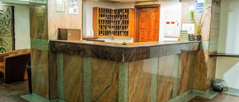 A reception area with a marble counter, a wooden door, and a bulletin board.