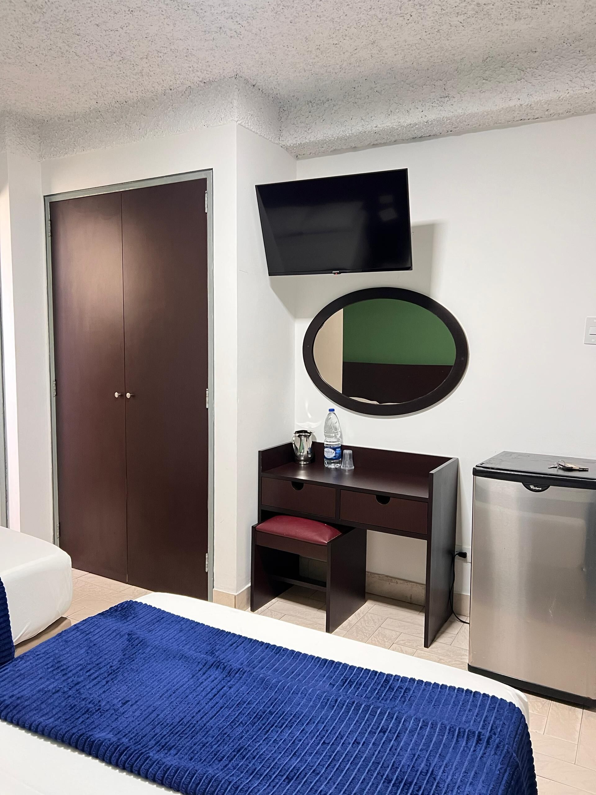 Une chambre d’hôtel comprenant un lit, un bureau avec un miroir, une télévision et un mini-bar.