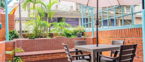 An outdoor patio area with a table and chairs, surrounded by brick walls and potted plants.