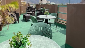 Een dakterras met buitenmeubilair, uitzicht op bergen en lichtslingers.
