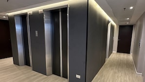 Een moderne hal met een rij liften en een houten vloer.