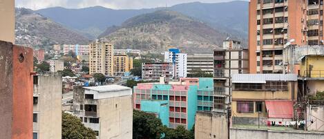 A densely packed urban area with multi-story buildings, some with balconies, and a mountainous backdrop.