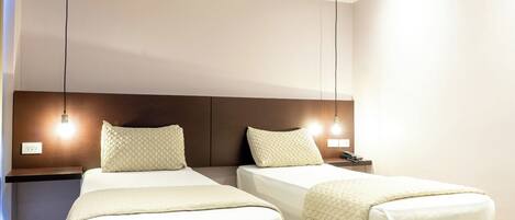 A hotel room with two beds, a wooden headboard, bedside lamps, a nightstand, and a telephone.