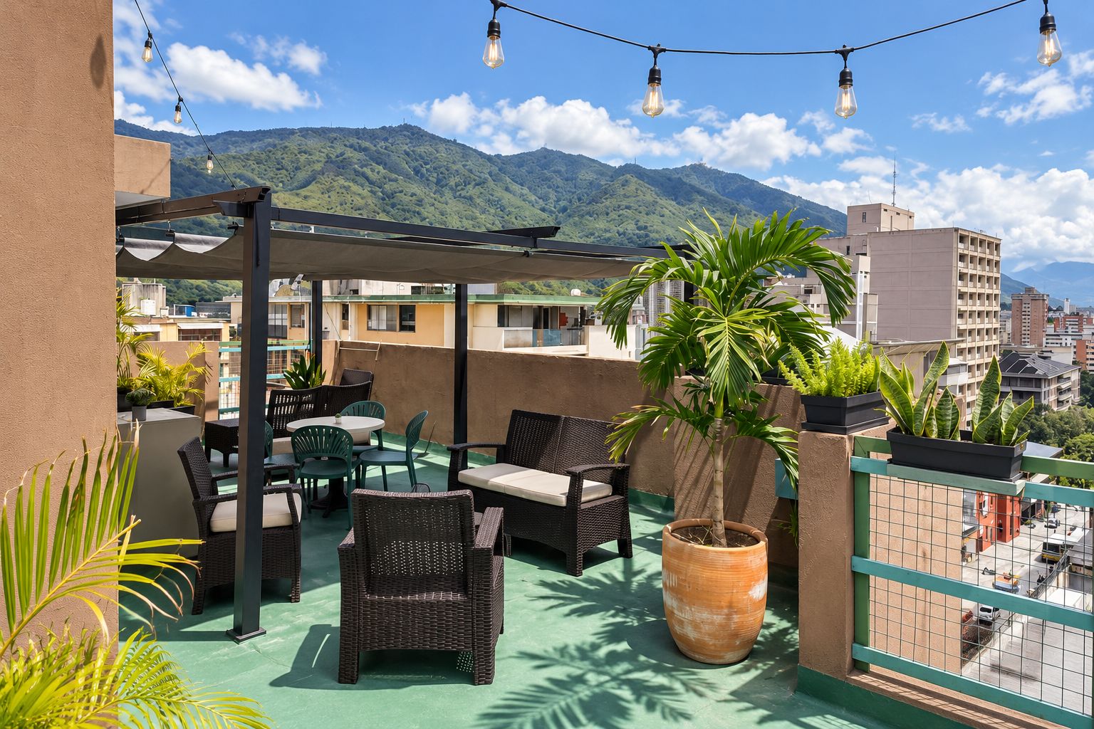 A rooftop terrace with outdoor furniture, a potted plant, and a view of a mountainous landscape.