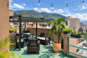 Terraza en la azotea con mobiliario exterior, una planta en maceta y vistas a un paisaje montañoso.