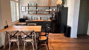 Una cocina con armarios de madera, un refrigerador negro y una mesa de comedor con sillas.