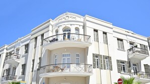 Un edificio de varios pisos con balcones, ventanas grandes y un cielo azul despejado.