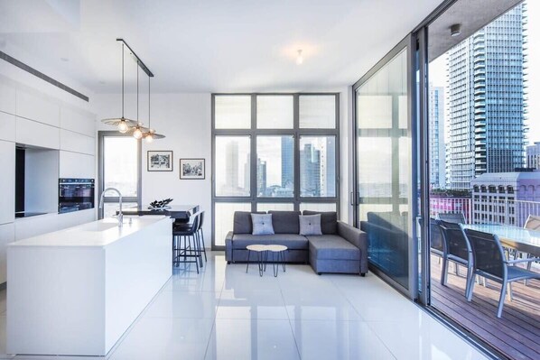 A modern living space with a kitchen, dining area, and seating area with a view of the city.