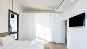 Habitació d'hotel moderna amb un llit gran, una televisió penjada a la paret i un armari amb portes corredisses.
