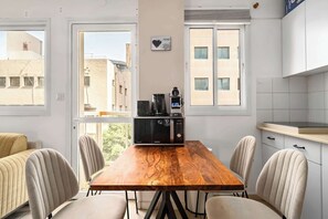 A modern kitchen with a wooden table, chairs, and a microwave. - Stylish 2BR by Rothschild by HolyGuest (Tel Aviv)