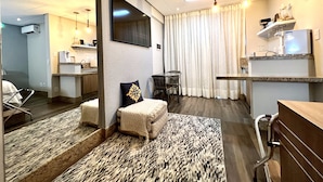Une chambre d’hôtel dotée d’une kitchenette, d’un coin repas, d’un grand miroir et d’un tapis à motifs.