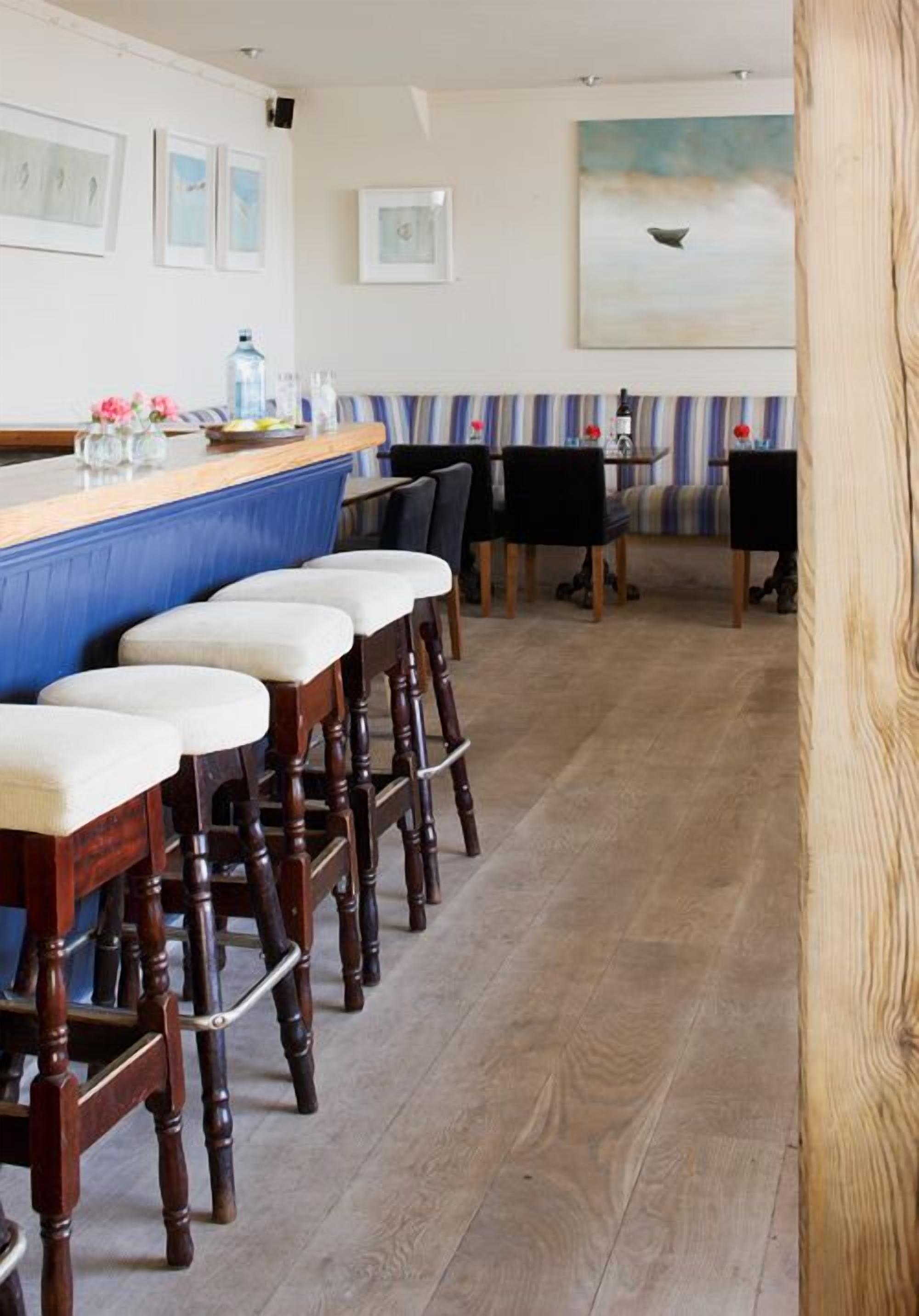 Angolo bar con sgabelli di legno, un bancone e quadri appesi al muro.