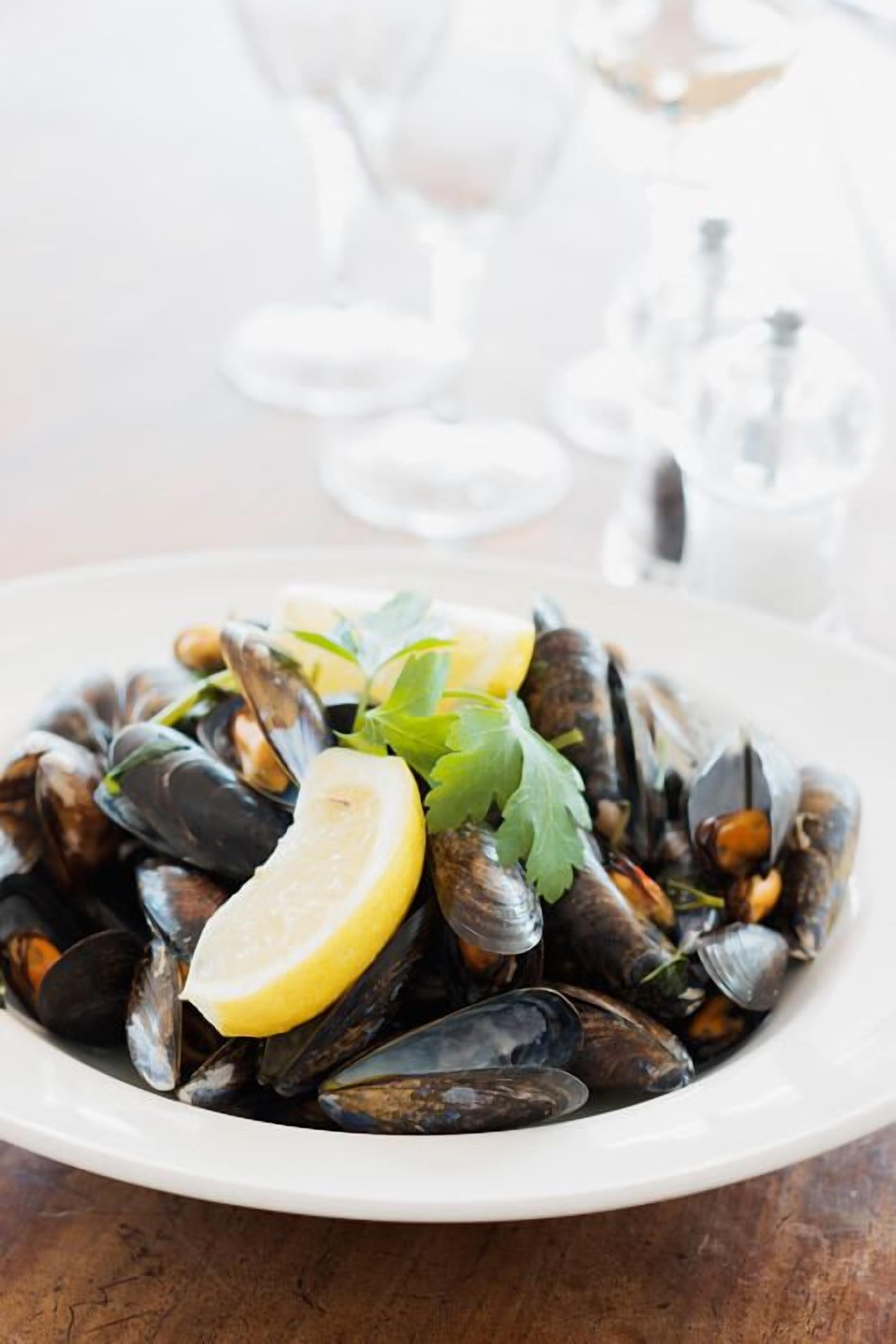 Une assiette de moules garnie de citron et de persil.