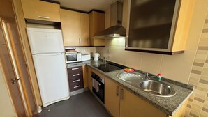 Cocina compacta equipada con refrigerador, microondas, tostadora y pileta.