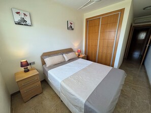 A neatly arranged bedroom with a bed, bedside tables, and a wardrobe. - Beautiful 2 Bedroom 2 Bathroom Apartment With Several Pools (Roquetas de Mar)