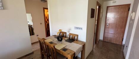 Un comedor con mesa y sillas de madera, un equipo de aire acondicionado y piso de baldosas.