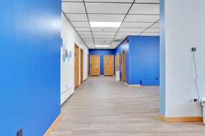 A hallway with blue walls, wooden doors, and a tiled ceiling. - Foothills Lodge & Diner (Malone)
