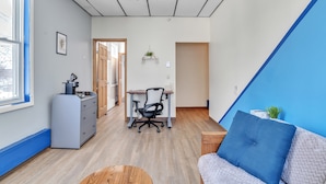 A modern, well-lit room with a desk, office chair, and a blue accent wall. - Foothills Lodge & Diner (Malone)