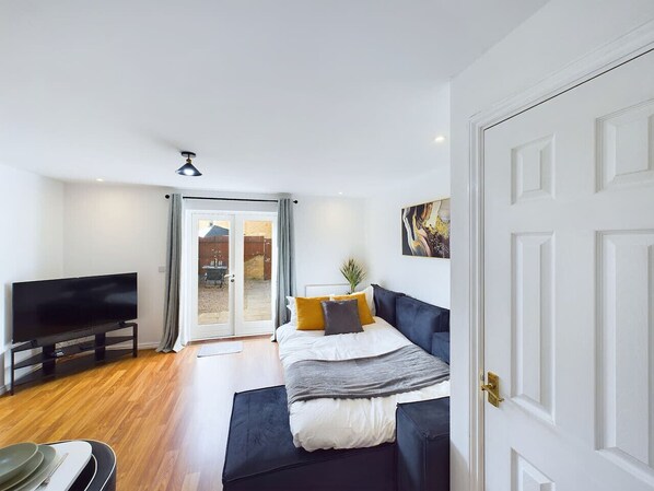 Un dormitorio con cama, televisor y puerta corrediza de vidrio que da a un área exterior.