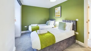Habitación con dos camas, una lámpara y una puerta.