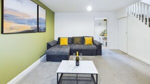 Una sala de estar con un sofá modular gris, una mesita de centro blanca y un cuadro en la pared.