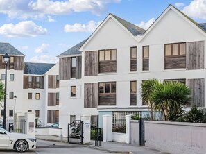Stylish residential building with a symmetrical facade, featuring windows with shutters and a flat roof.