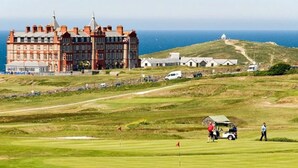 Un campo de golf con un edificio grande y una colina con una estructura en la cima.