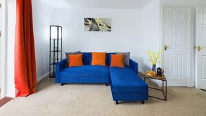 A living room with a blue sectional sofa, a coffee table, and a painting on the wall.