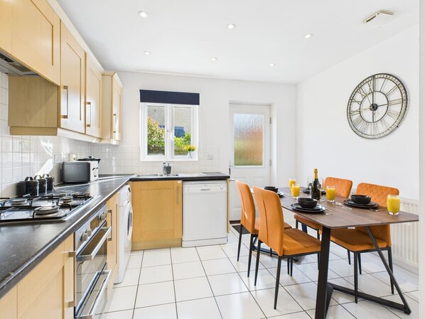 Una cocina moderna con comedor, que incluye lavavajillas, estufa y una mesa con sillas.