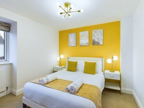 A hotel room with a bed, two bedside tables, a window, and a ceiling light fixture.