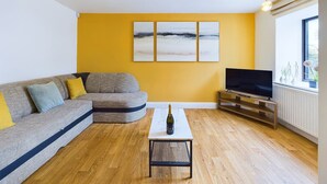Una sala de estar con un sofá modular, un televisor de pantalla plana, una mesa de centro y un ventanal con vistas.