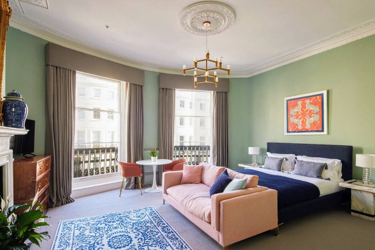 Una habitación de hotel con cama, sofá, mesa de comedor y balcón.