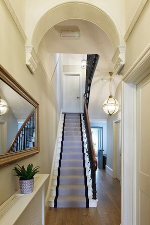 A grand staircase with a wooden handrail and a black and white striped carpet. - Lansdowne House (Hove)