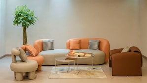 Una sala de estar moderna con un sofá, un reposapiés, una mesa de centro y una planta en maceta.