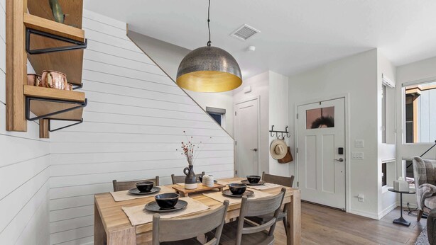 Een eethoek met een houten tafel, stoelen en een hangende lamp.