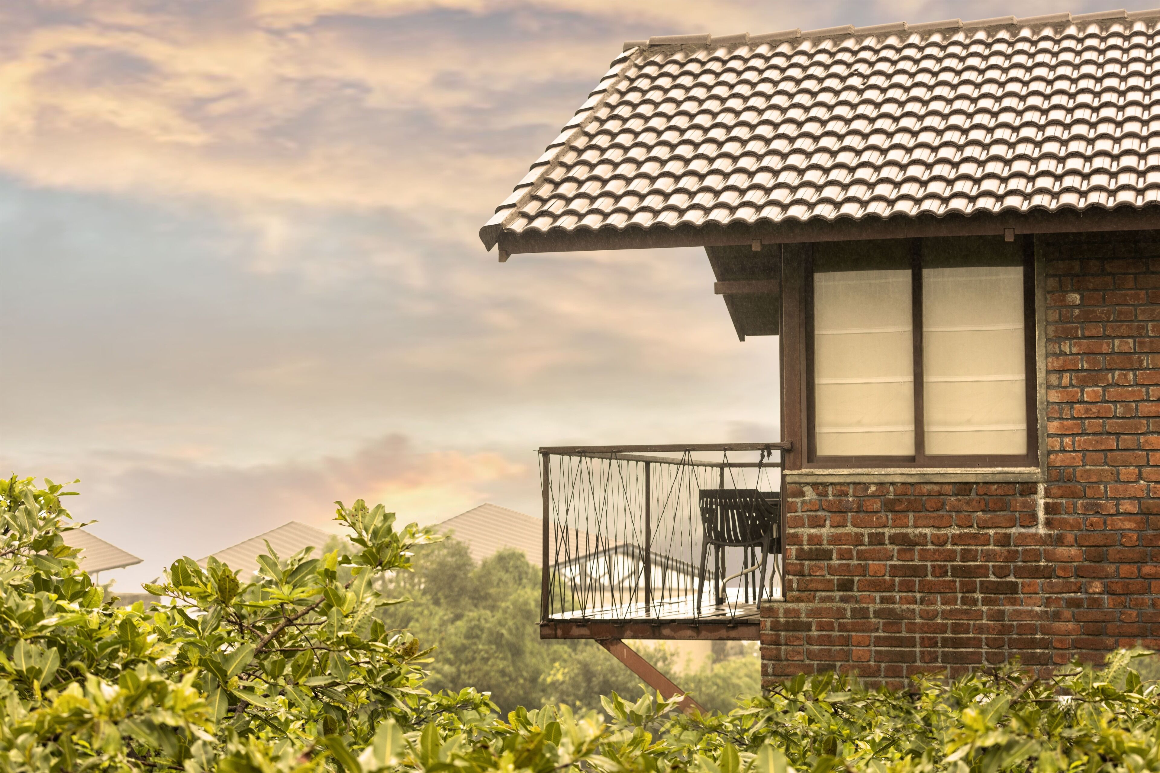 A brick building with a tiled roof and a balcony with a metal railing.