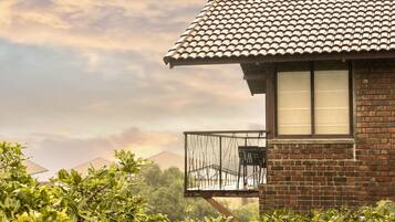 A brick building with a tiled roof and a balcony with a metal railing.