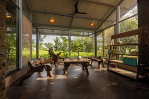 Um quarto espaçoso com uma grande parede de vidro, móveis de madeira e um ventilador de teto.