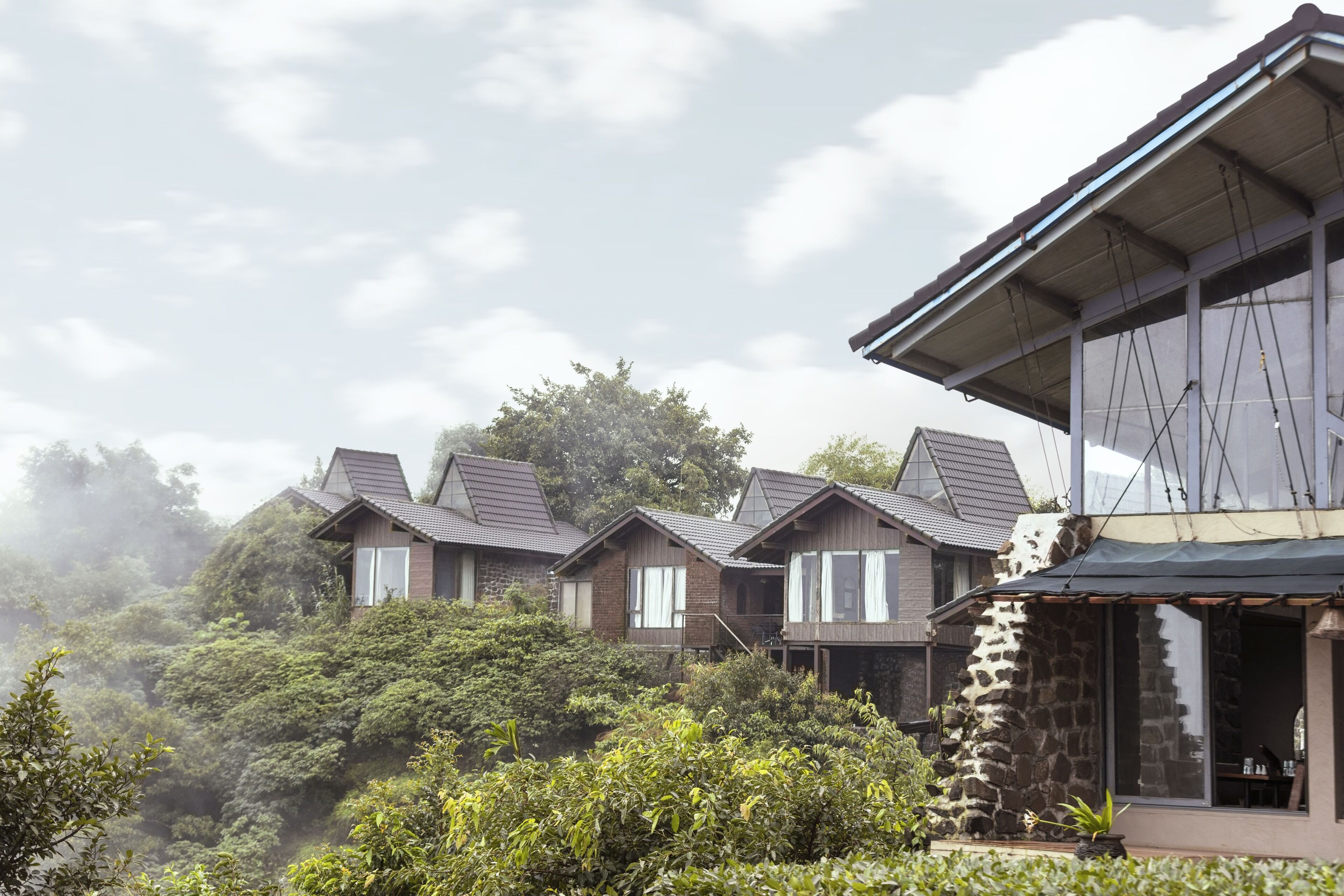 A row of traditional-style houses with pitched roofs, surrounded by lush greenery and trees.