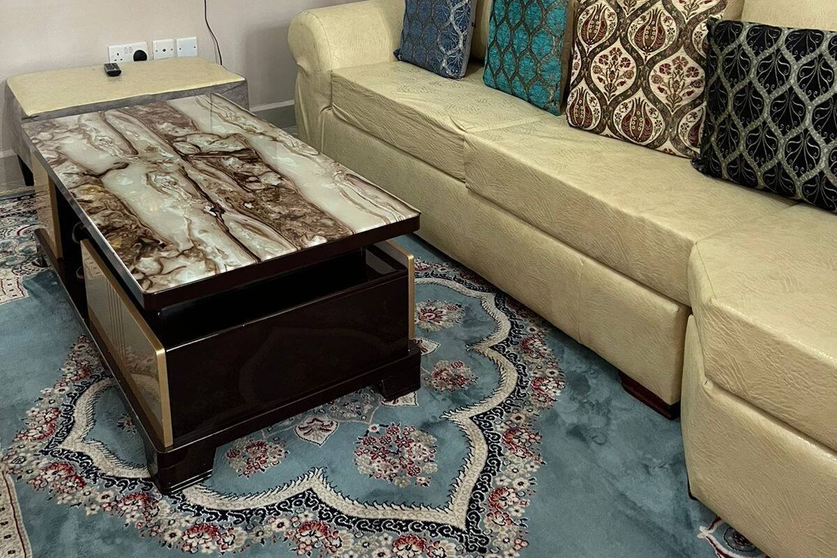 A living room with a sofa, a coffee table, and a TV mounted on the wall.