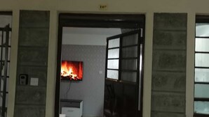 Une pièce avec un téléviseur diffusant une image de feu de cheminée, un canapé et un tapis.